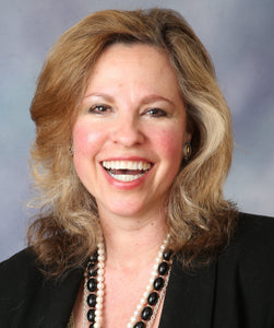 Photo of Caryn Kocel smiling wearing a black jacket and necklace